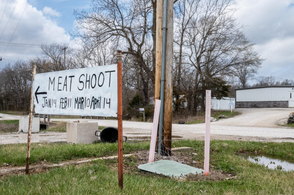 A rural scene featuring a handmade sign that says "Meat Shoot" with the list of dates in January, February, March and April